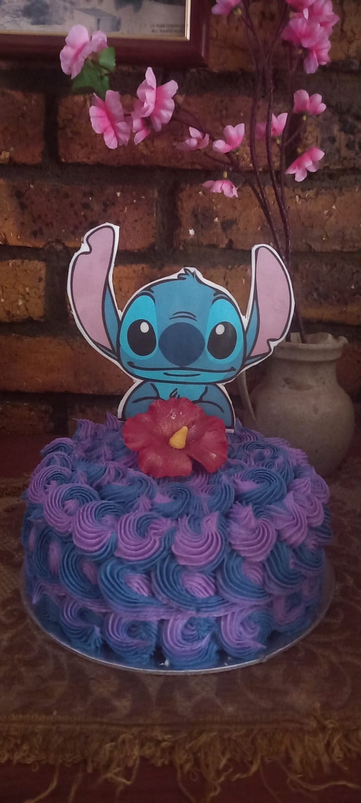 Stitch themed cake with blue and purple frosting rosettes and hibiscus flower